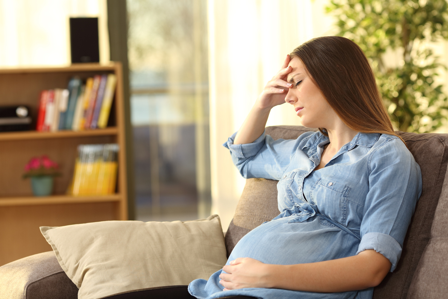 Pregnant woman on a couch coping with pregnancy anxiety before prenatal counseling in Los Angeles